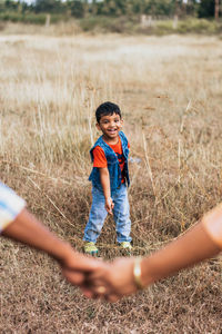 Couple holding hands against son on field