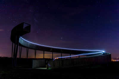 Illuminated built structure on field against sky at night