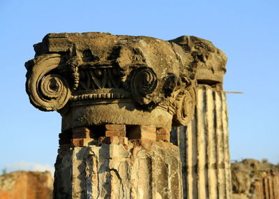 Close-up of old sculpture against clear blue sky