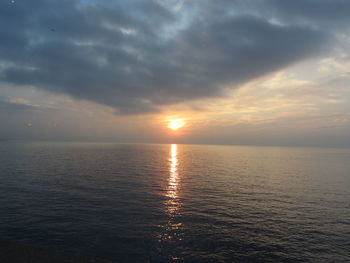 Scenic view of sea against dramatic sky during sunset