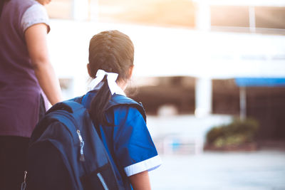 Side view of mother taking daughter to school