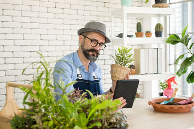 Portrait of senior man using laptop while standing against brick wall