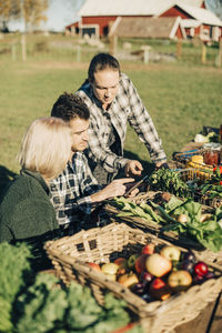 Male and female farmers using digital tablet with organic vegetables on table