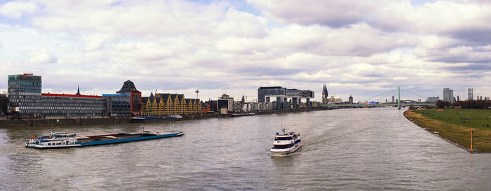 Boats on river by buildings in city against sky