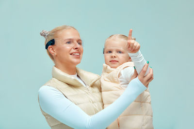 Mother and daughter wearing futuristic glasses while gesturing against blue background