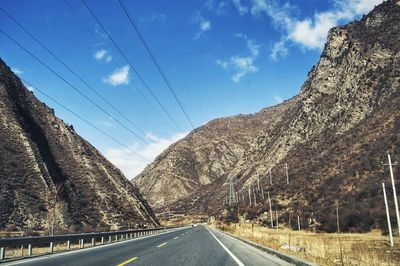 Road by mountains against sky