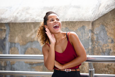 Young woman smiling while standing against wall