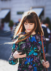 Young woman using smart phone while standing outdoors