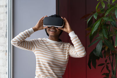 Amazed african american woman testing modern high-tech vr helmet, getting 3d experience at home