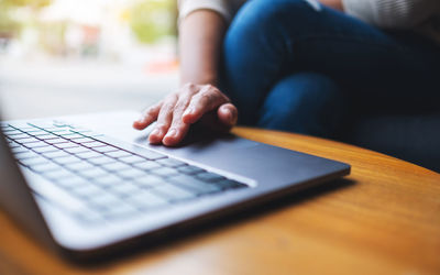 Closeup image of a woman working and touching on laptop computer touchpad on the table