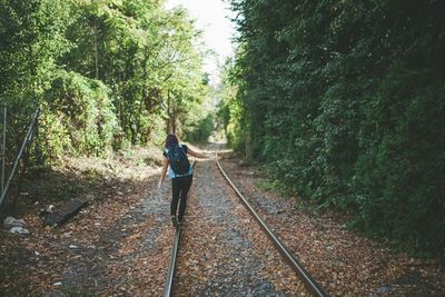 Rear view of man walking on railroad track