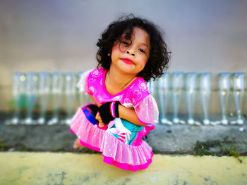 Portrait of girl wearing make-up while crouching by glasses