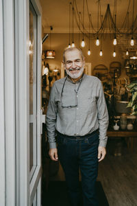 Smiling senior male entrepreneur standing near door of home interior store