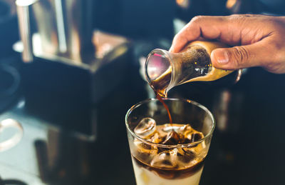 Close-up of hand pouring coffee in glass