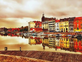 Reflection of cityscape in river against sky