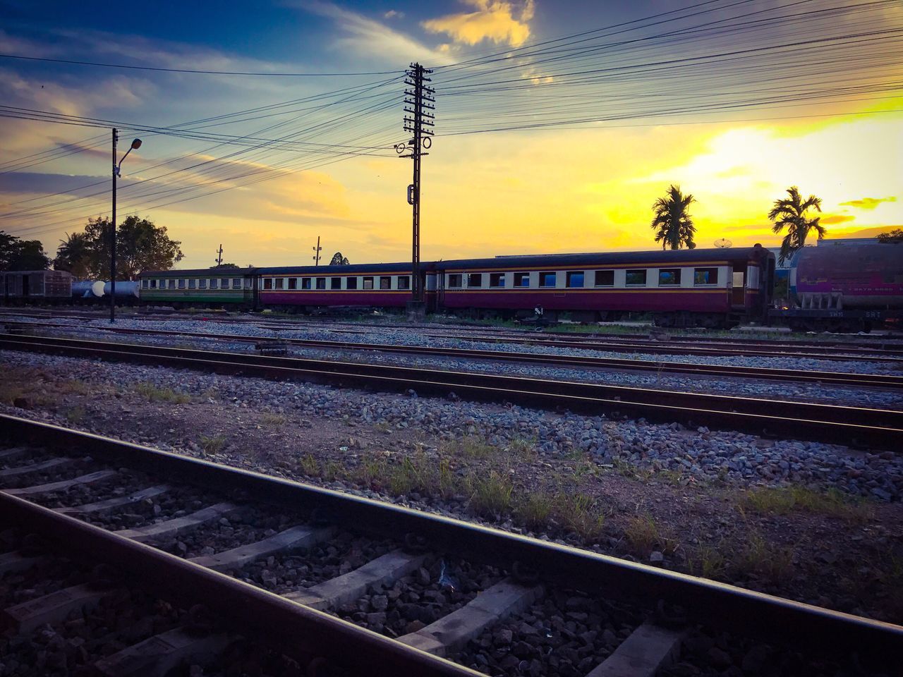 VIEW OF RAILWAY TRACKS AGAINST SKY AT SUNSET
