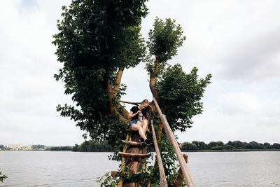 Rear view of woman standing by lake against sky