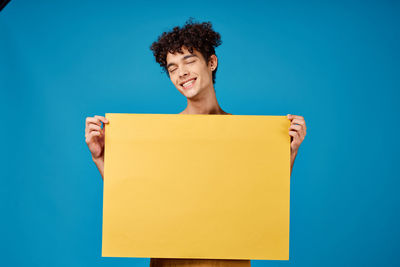 Portrait of smiling young woman against blue background