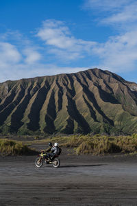 A motorbikewith two people driving in an amazing landscape with green hills as the background