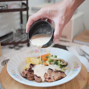 Cropped image of hand pouring coffee in cup on table