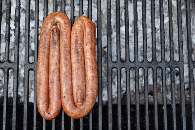A top view shot of a sausage being grilled on a grill outdoors