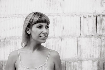 Portrait of smiling young woman standing against wall