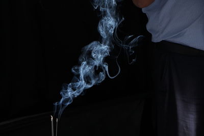 Close-up of incenses burning against black background