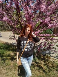 Redhead woman standing against blooming tree