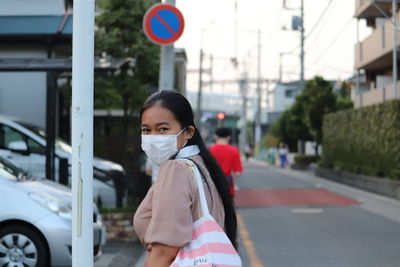 Portrait of woman standing on road in city