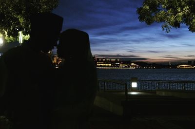 Rear view of man against illuminated trees against sky