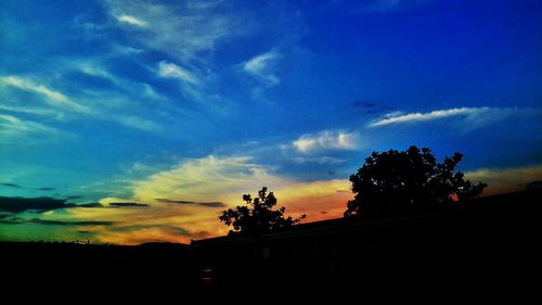 Silhouette of trees against cloudy sky