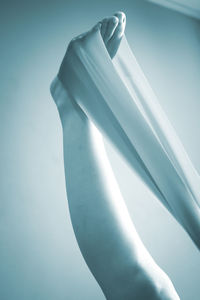 Low section of person doing yoga with resistance band against white background