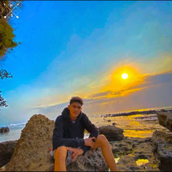 Portrait of man on rock against sky