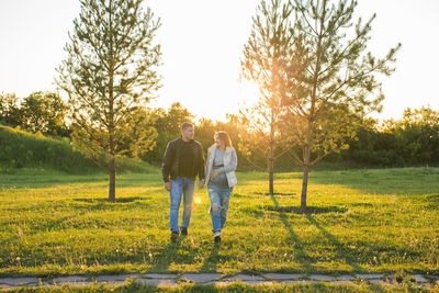 Rear view of couple walking on field against sky