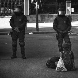 Police men standing by homeless female hipster on road in city