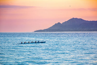 Hawaiian outrigger crew paddling at sunset