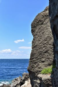 Rock formation by sea against sky