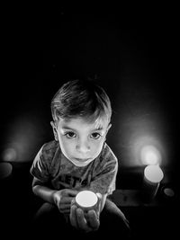 Portrait of boy holding burning tea light in dark