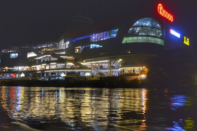 Illuminated buildings by river at night