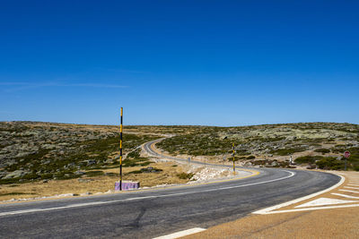 Empty road against clear blue sky