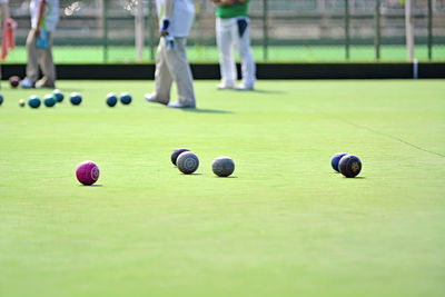 Low section of people playing lawn bowling at playing field