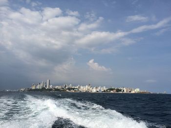 Scenic view of sea and cityscape against sky