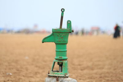 Green water pump on field against sky