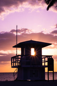 Lifeguard hut on beach against sky during sunset