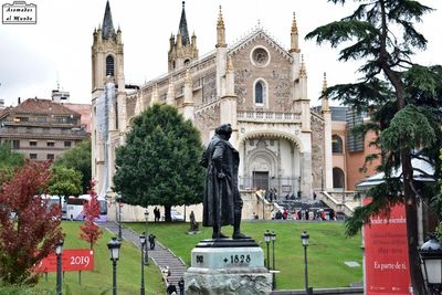 Statue amidst trees and buildings against sky