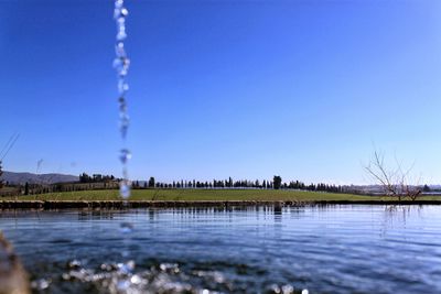 Scenic view of lake against clear blue sky