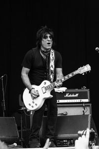 Young man playing guitar against black background