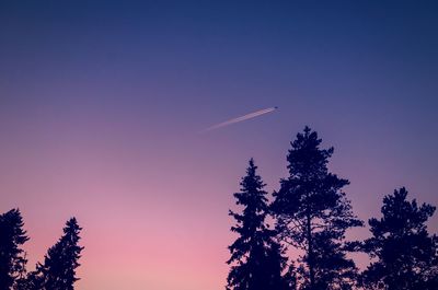 Silhouette trees against clear sky at sunset