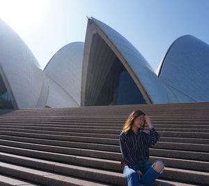 Woman sitting on staircase against sky