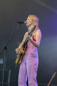 Young woman playing guitar at music concert